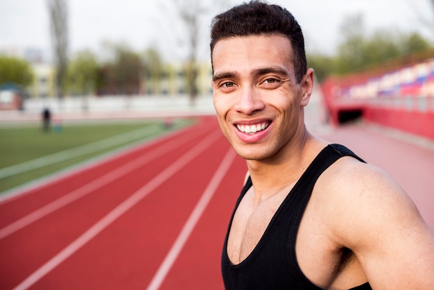 Smiling portrait of a male athlete on race track at stadium