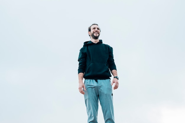 Smiling portrait of a man standing against blue sky