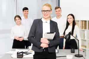 Free photo smiling portrait of a young businesswoman holding digital tablet in hand standing in front of her colleague