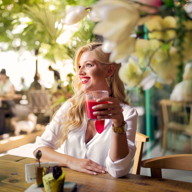 Free Photo smiling portrait of a young woman holding glass of juice in the restaurant