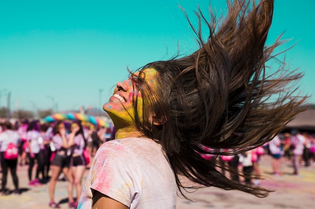 Free photo smiling portrait of a young woman with holi color tossing her hair