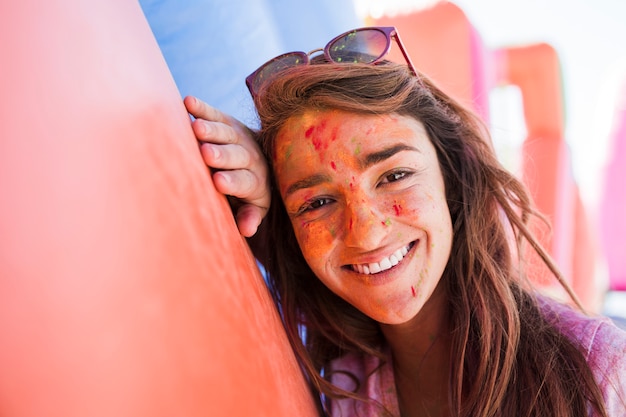 Free photo smiling portrait of a young woman with holi colors on face powder looking at camera