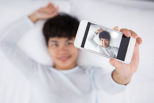 Smiling Pretty Asian Woman Taking Selfie in Bed