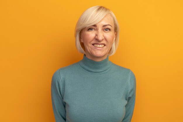 Free photo smiling pretty blonde slavic woman looks at front isolated on orange wall