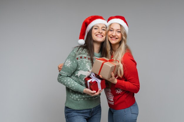 Smiling pretty girlfriends with Christmas gifts.