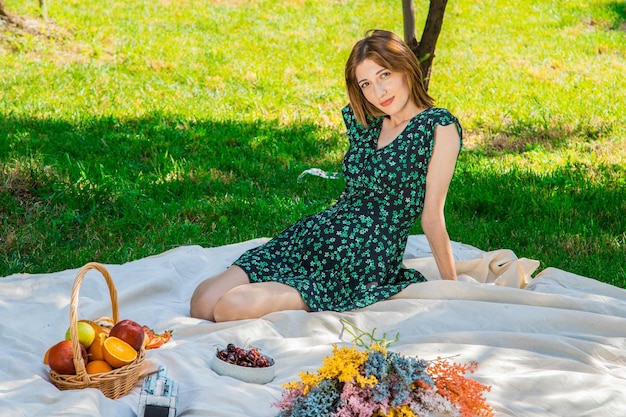 Smiling pretty young woman in hat on picnic in park