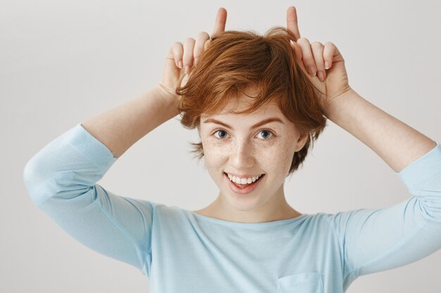 Smiling redhead girl posing against the white wall