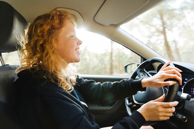 Smiling redhead woman driving car