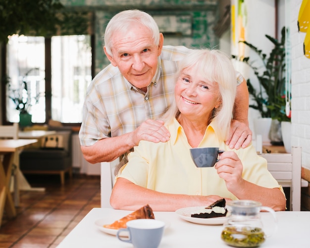 Smiling senior couple sitting in cafe with tea cups