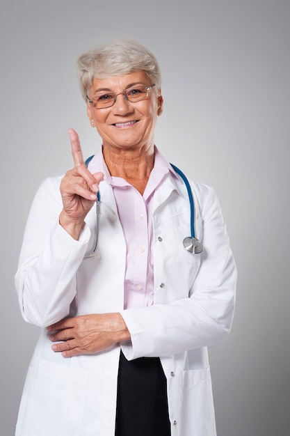 Smiling senior doctor pointing by finger