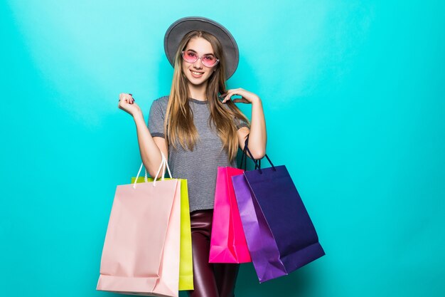 Smiling shopping woman smiling and wearing a hat isolated over green background