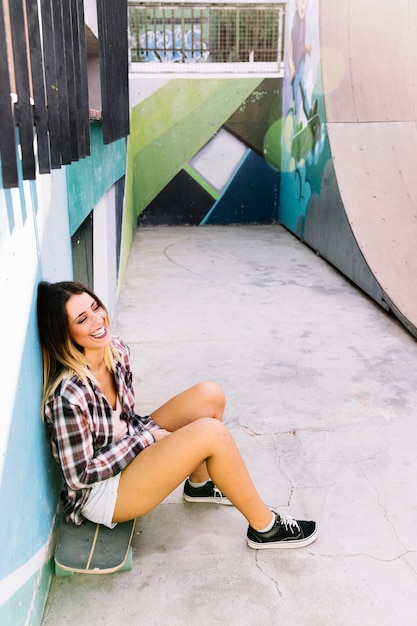 Free Photo smiling skater girl sitting on skateboard