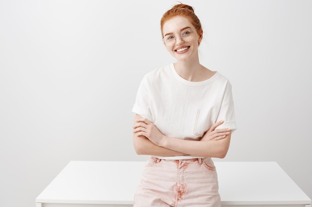 Free photo smiling stylish redhead girl lean on table, looking determined