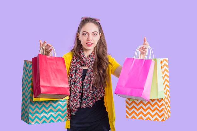 Free photo smiling stylish woman showing colorful paper bag