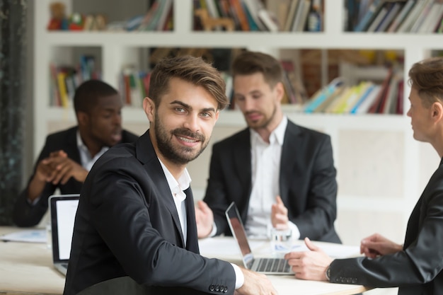 Smiling team leader looking at camera on group corporate meeting 