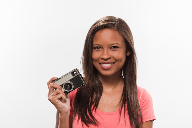 Smiling teenage girl holding camera on white backdrop