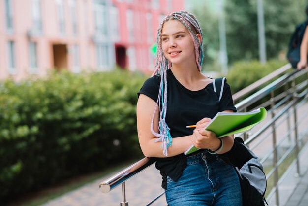 Smiling thinking schoolgirl with textbook