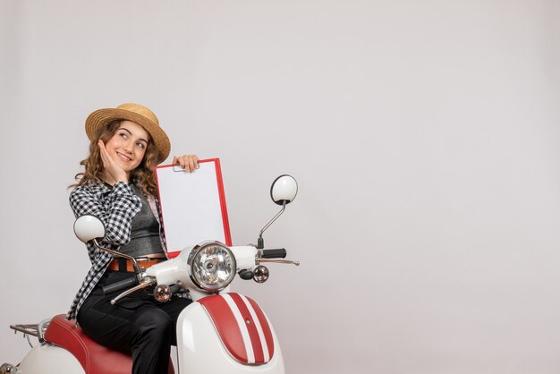 smiling traveller girl on moped holding red clipboard free space