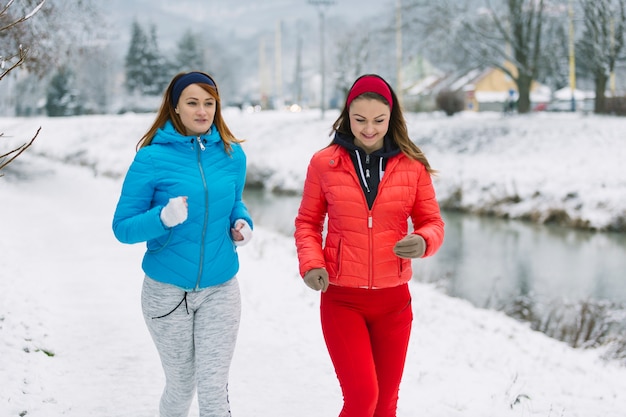 Smiling two female friends jogging in winter season