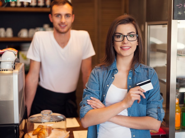 Smiling waiter and beautiful female customer with credit card