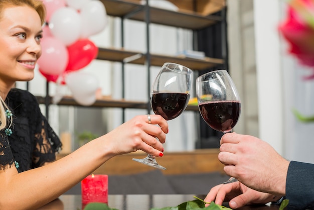 Free photo smiling woman clanging glasses of wine with man at table