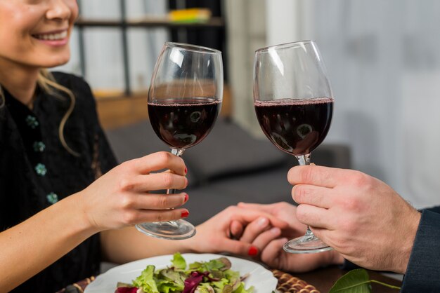 Smiling woman clanging glasses of wine with man at table