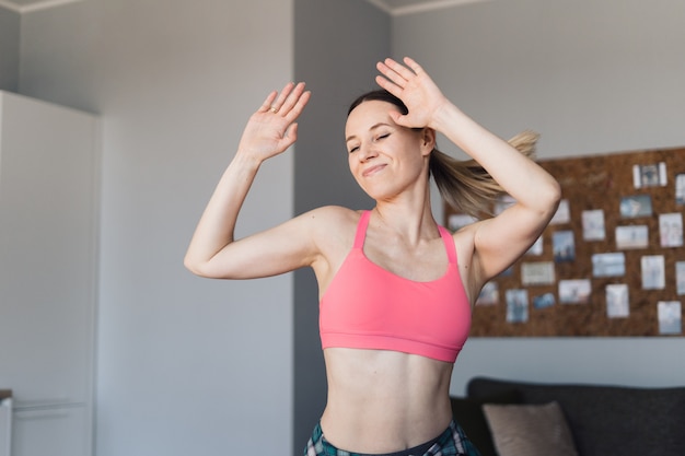 Smiling woman dancing in the middle of the living room enjoying herself and life