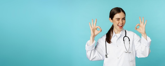 Smiling woman doctor professional medical worker showing okay ok sign in approval recommending clini