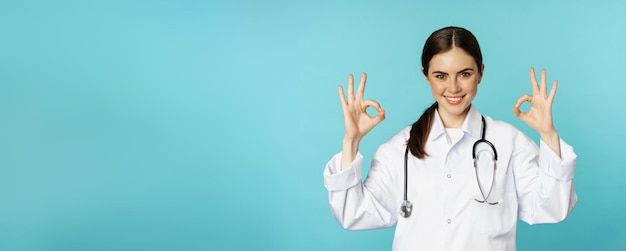 Free Photo smiling woman doctor professional medical worker showing okay ok sign in approval recommending clinic quarantine campaign torquoise background