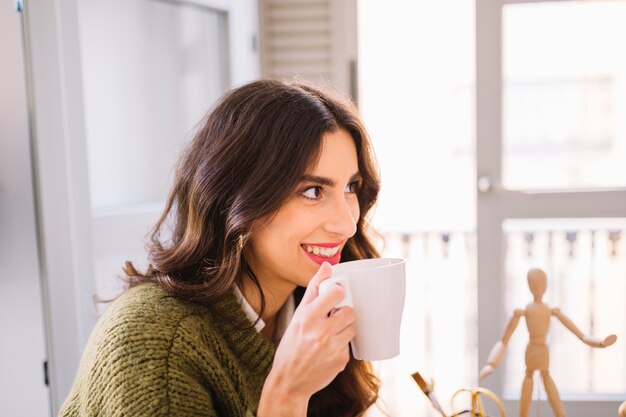 Smiling woman drinking hot beverage