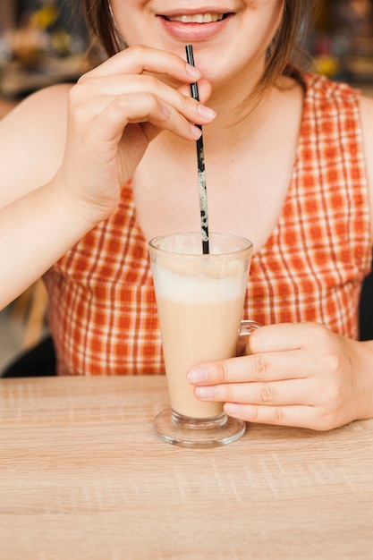 Free photo smiling woman drinking latte coffee at cafeteria