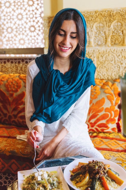 Free photo smiling woman eating in arab restaurant