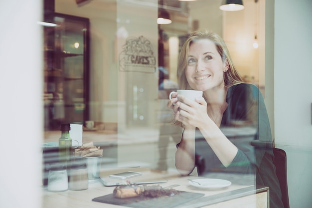 Smiling woman enjoying hot drink in cafe