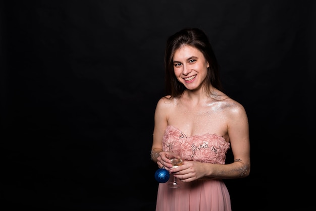 Smiling woman in evening dress with glass and ornament ball 