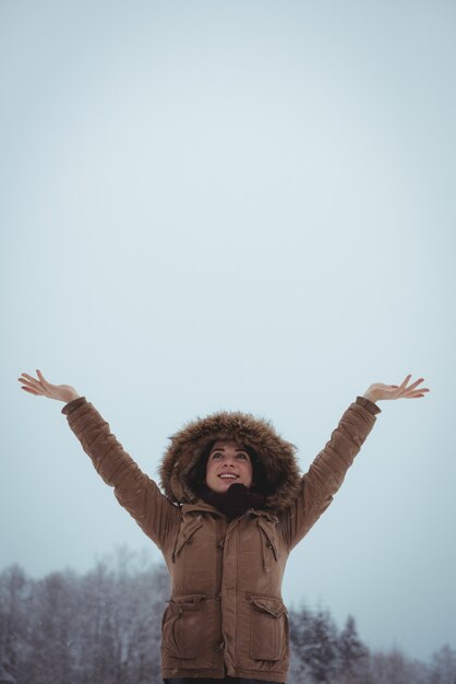 Smiling woman in fur jacket enjoying the snowfall