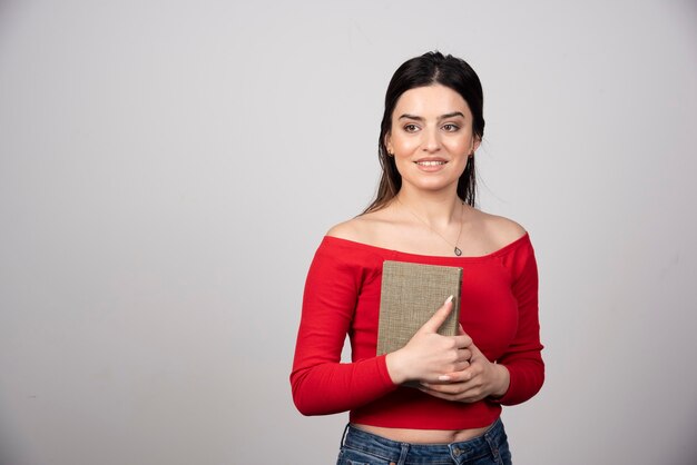 Smiling woman holding a book and looking away.