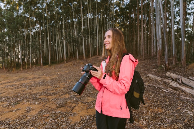 Free Photo smiling woman holding camera in forest