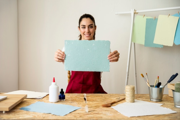 Free photo smiling woman holding handmade blue paper