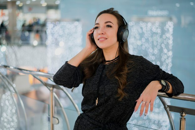 Smiling woman holding headphones on head in shopping mall