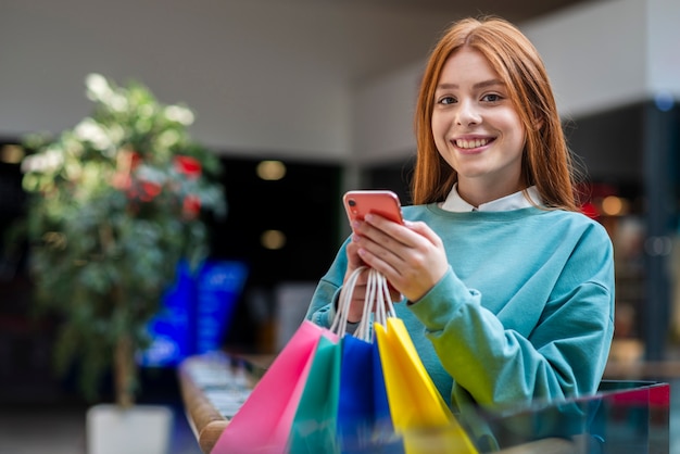 Free photo smiling woman holding phone and looking at photographer