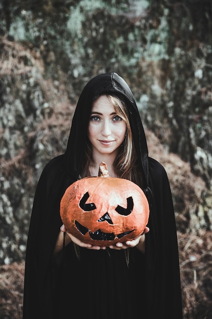 Smiling woman holding pumpkin in park