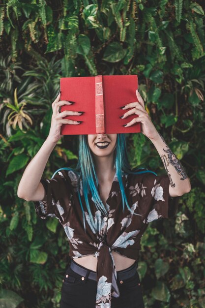 Smiling woman holding red book in front of her eyes