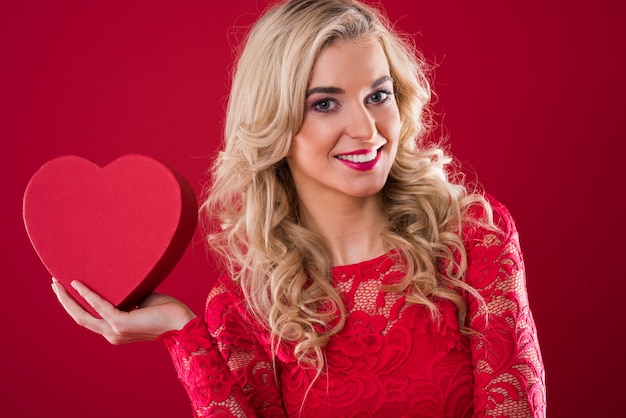 Smiling woman holding red heartshape box