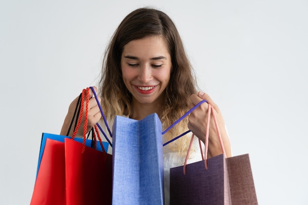 Free photo smiling woman holding shopping bags and peeping into one of them.