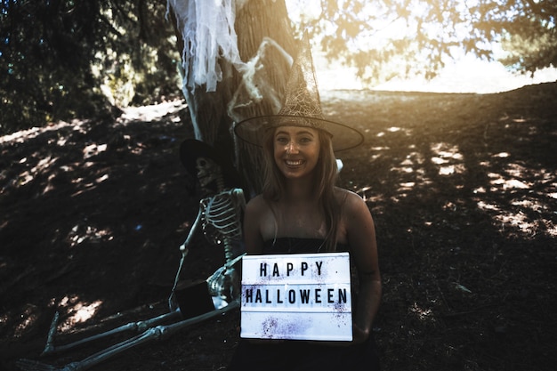 Free photo smiling woman holding signboard in sunlit thicket