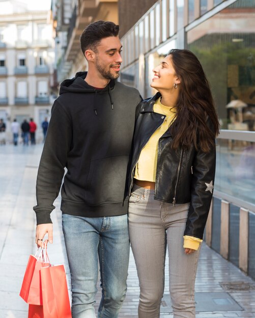 Smiling woman hugging young positive man with shopping packets