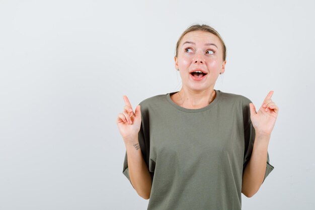 The smiling woman is pointing up with forefingers on white background