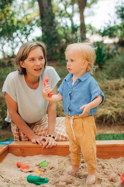 Smiling woman looking after her child in sandpit