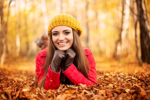 Smiling woman lying down on autumn leaves