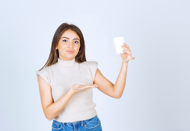 A smiling woman model showing a plastic cup and posing.